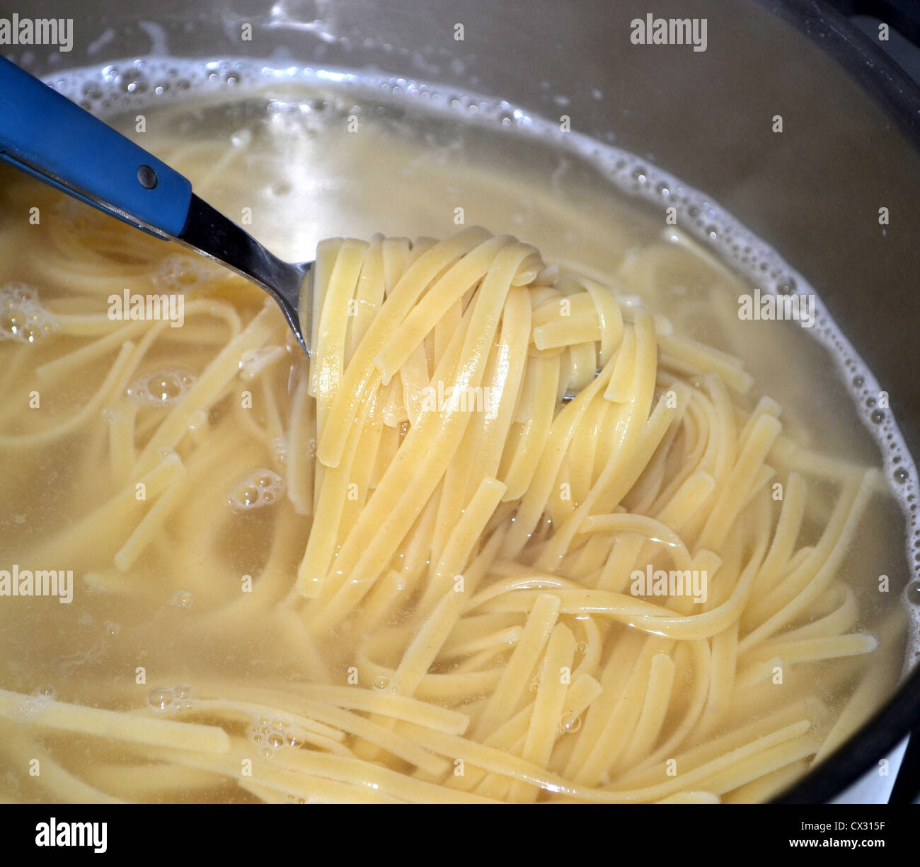 Linguine (anche "Linguini") è una forma di pasta - piatta come fettuccine e trenette. La cottura in pentola di acqua bollente Foto Stock