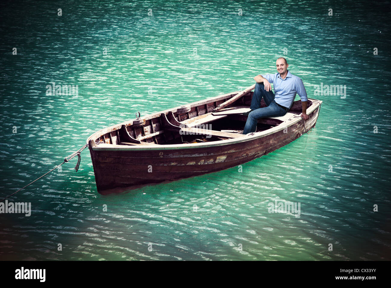 Uomo sulla vecchia barca nel lago verde Foto Stock