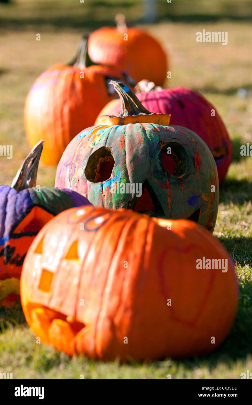 Le zucche che sono stati intagliati e dipinti dai bambini in un fall festival, asciutto nel pomeriggio sun. Foto Stock