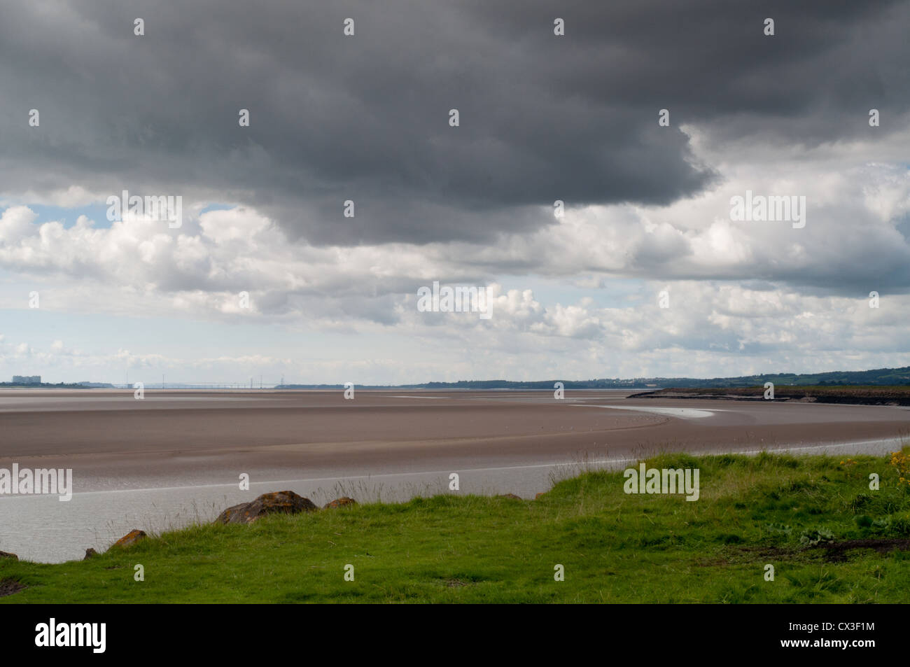 Fiume Severn a bassa marea in condizioni di scarsa luce solare con banca erbosa , cielo drammatico, nuvole Foto Stock