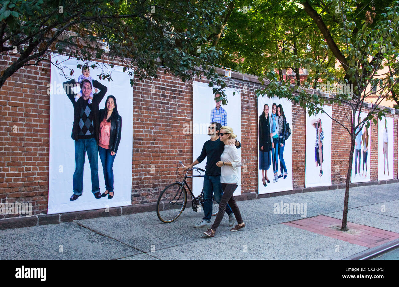 Su Prince Street nella sezione Nolita di New York City,​ un giovane con una bicicletta visualizza una parete del gigante blowups foto Foto Stock