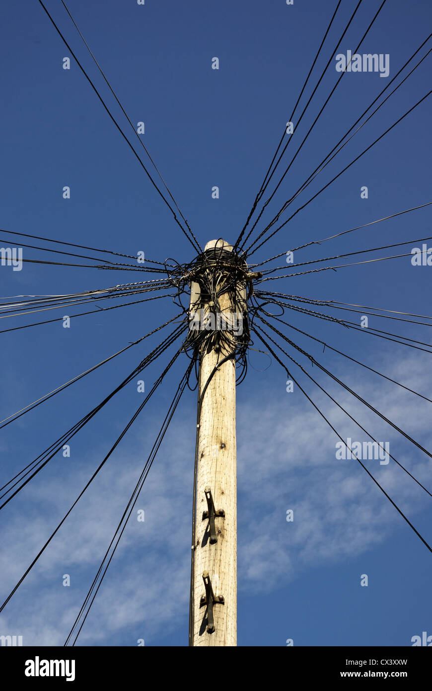 Un vecchio palo del telegrafo contro un cielo azzurro sfondo con fili di diffondere in tutte le direzioni Foto Stock