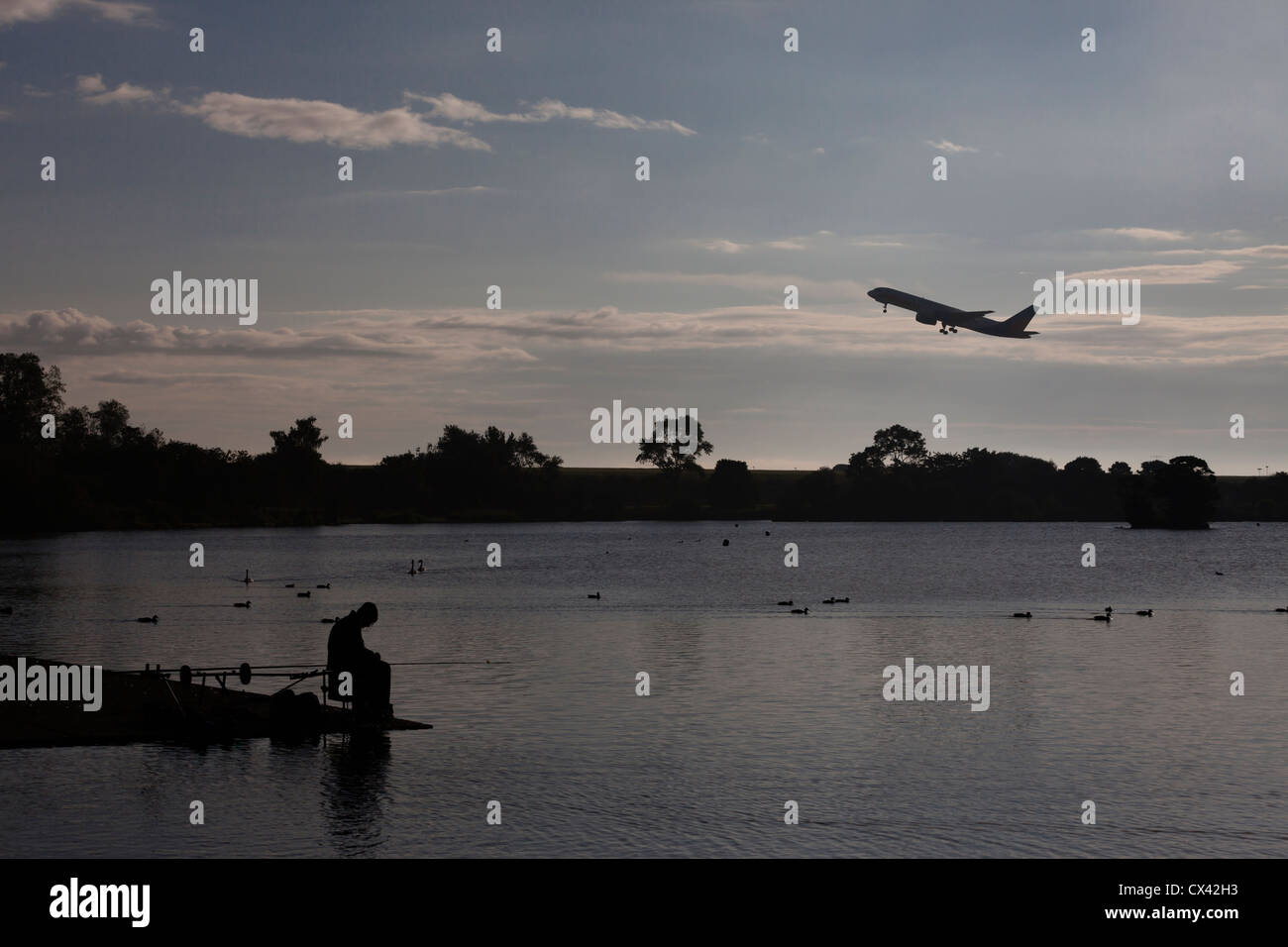 Uomo di pesca in Yeadon Tarn come un aereo decolla dall'aeroporto di Leeds Bradford. Foto Stock