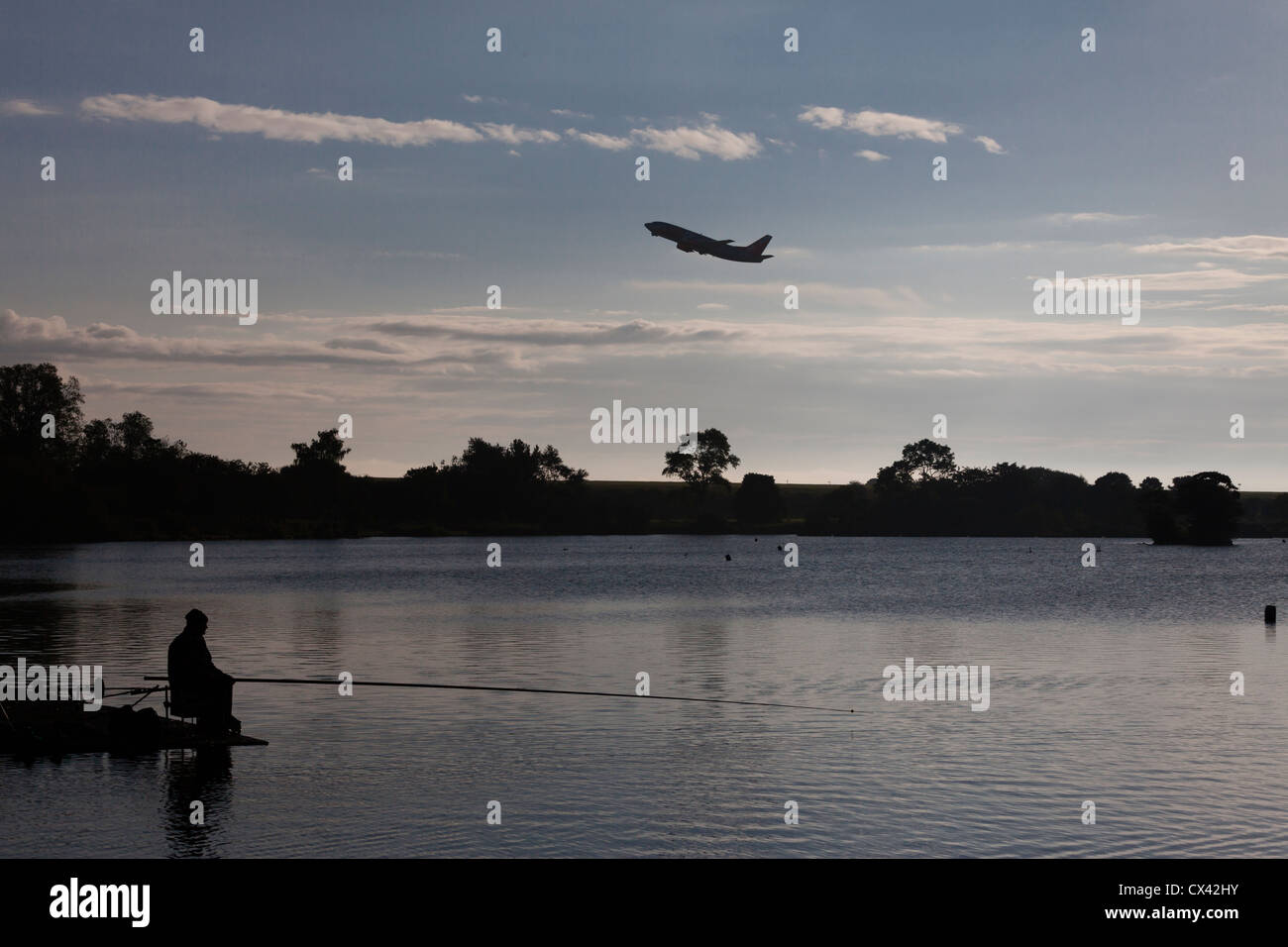 Uomo di pesca in Yeadon Tarn come un aereo decolla dall'aeroporto di Leeds Bradford. Foto Stock
