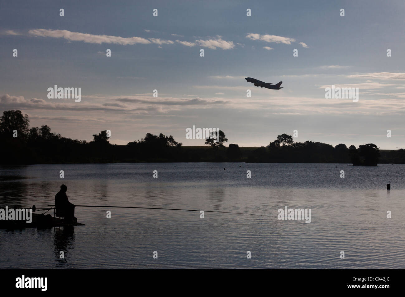 Uomo di pesca in Yeadon Tarn come un aereo decolla dall'aeroporto di Leeds Bradford. Foto Stock