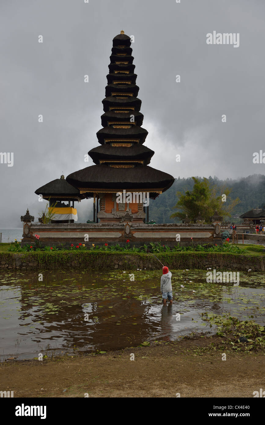 I bambini la pesca oltre il Meru del Danau Bratan su un giorno nuvoloso; Bali, Indonesia. Foto Stock