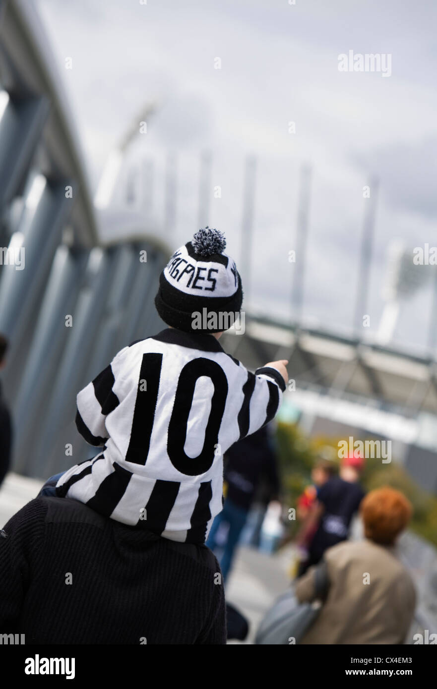 Un giovane Collingwood sostenitore corse su di suo padre a spalle sul suo modo di un AFL gioco. Melbourne, Victoria, Australia Foto Stock