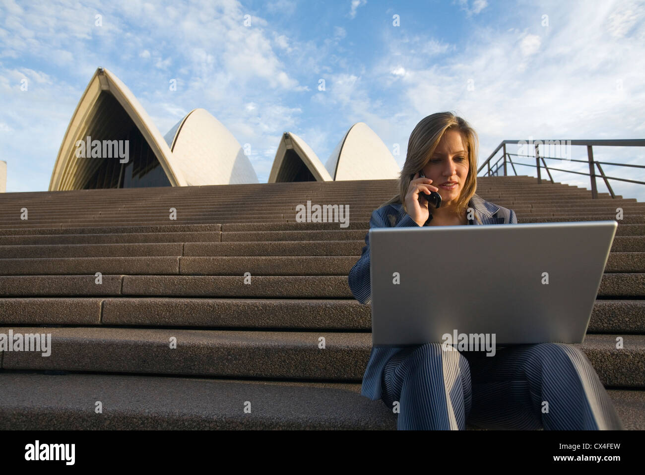 Imprenditrice sui gradini della Opera House con il telefono cellulare e il computer portatile. La Circular Quay, Sydney, Nuovo Galles del Sud, Australia Foto Stock