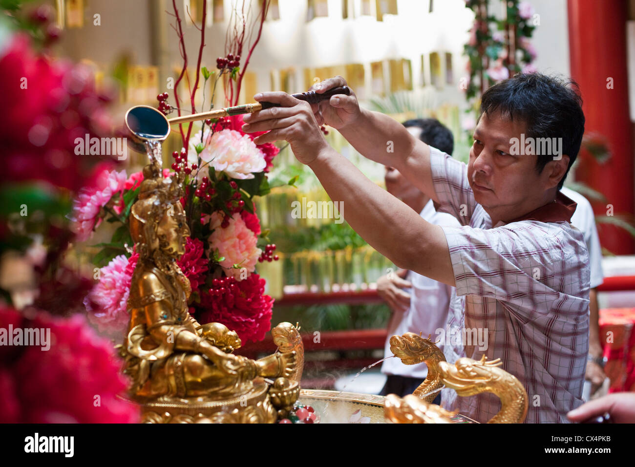 Un pellegrino si versa acqua santa in un santuario nel Dente del Buddha reliquia del tempio e museo, Chinatown, Singapore Foto Stock