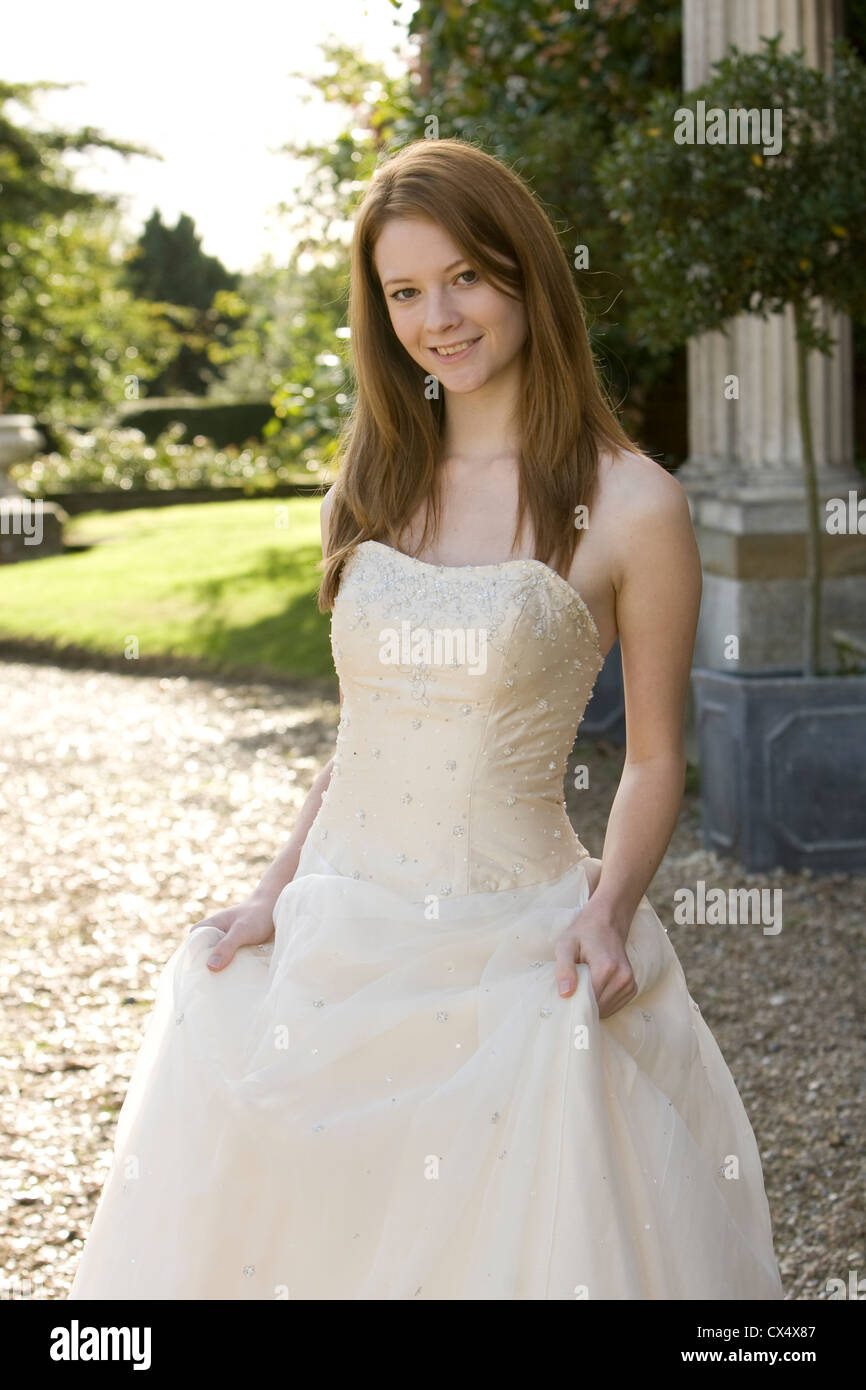 Giovane donna in crema senza spalline abito nuziale holding gonne in motivi di Sede statali Foto Stock