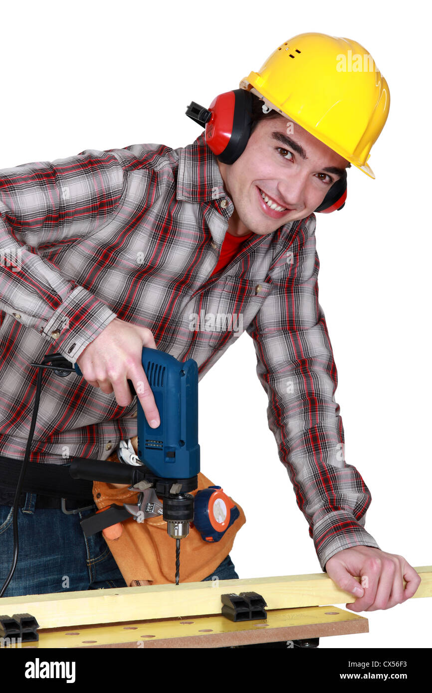 Giovane falegname tutti i sorrisi utilizzando drill Foto Stock