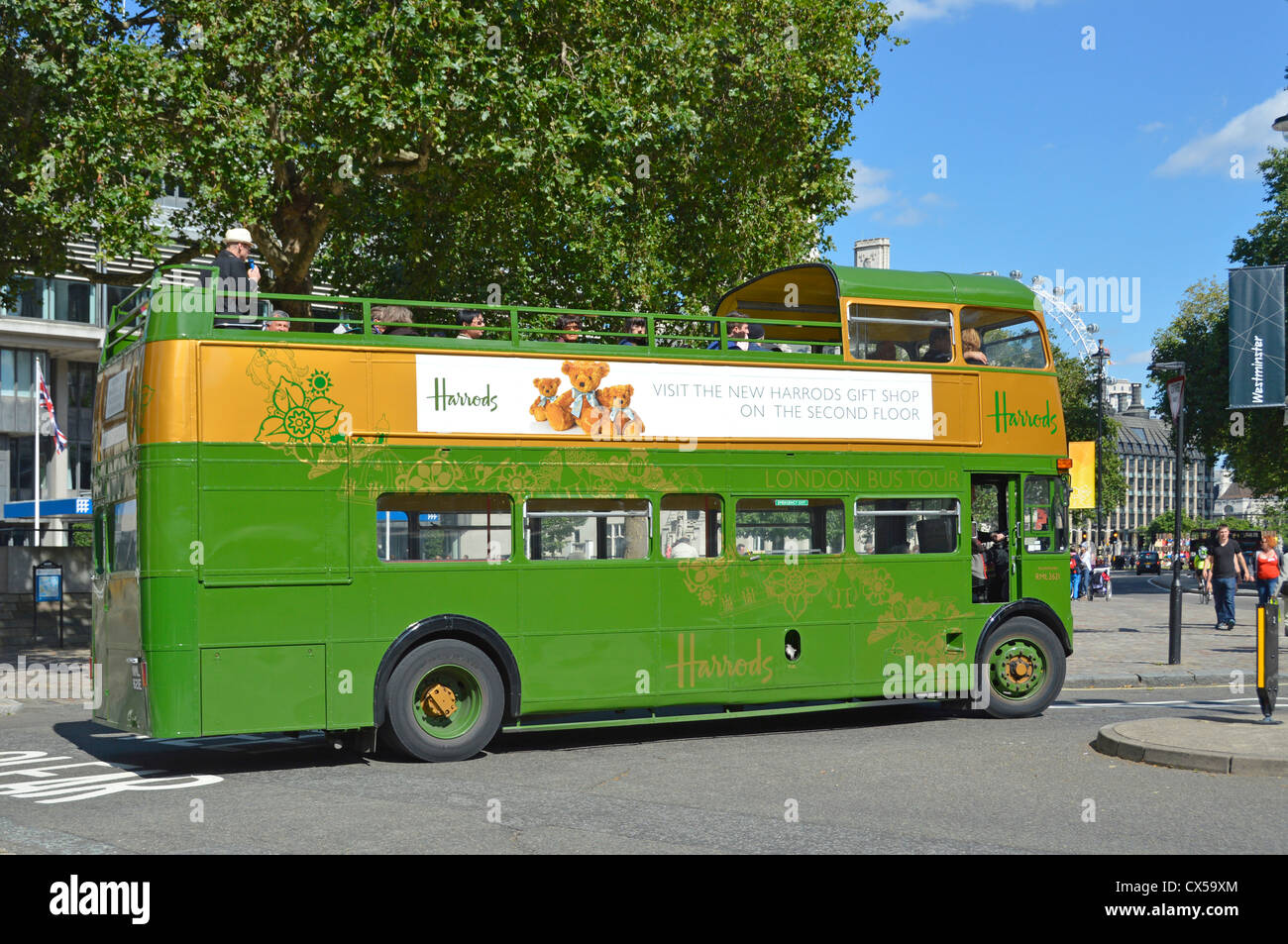 I turisti su Harrods open top classic convertito Routemaster tour bus per visite turistiche di Londra su un cielo blu giorno di estate London Eye al di là dell'Inghilterra, Regno Unito Foto Stock