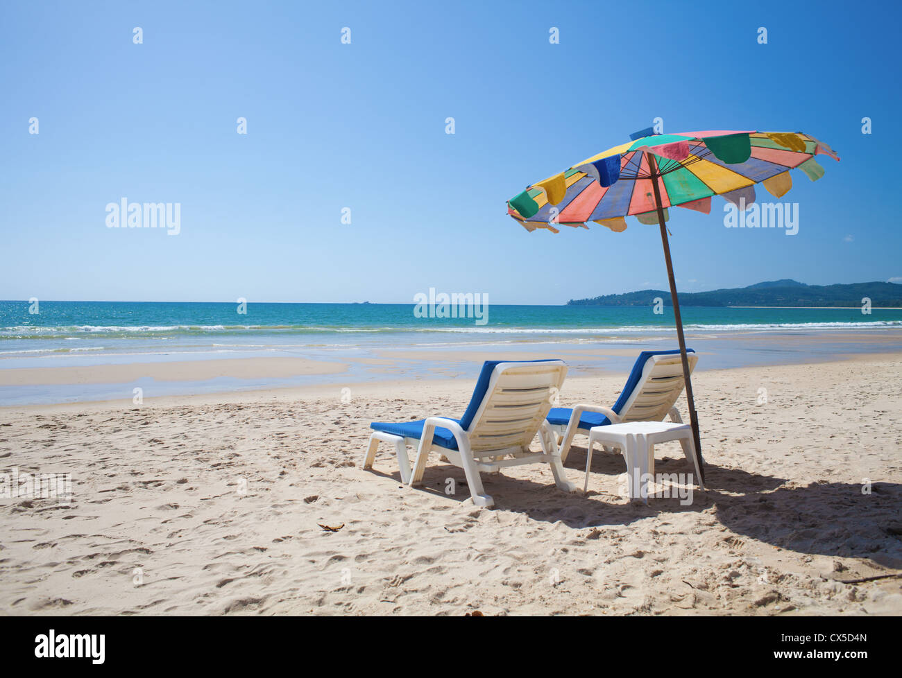 Ombrello coloratissimo e lettini da spiaggia sul mare Foto Stock