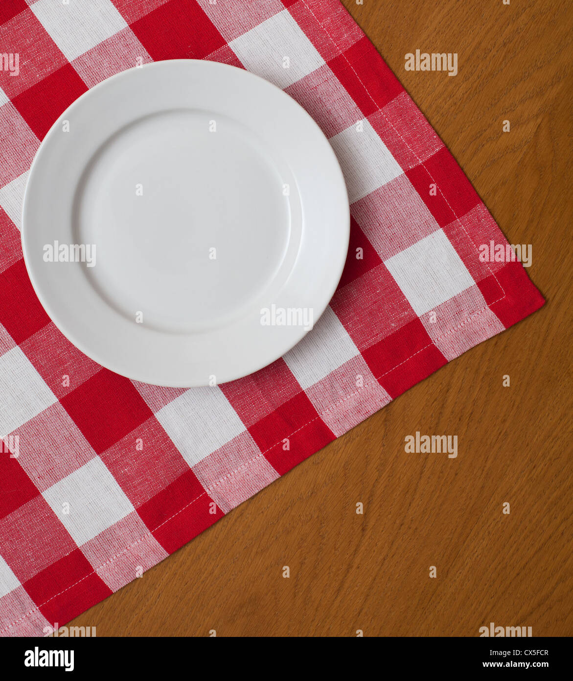 Piastra bianca sul tavolo di legno con rosso Gingham tovaglia Foto Stock