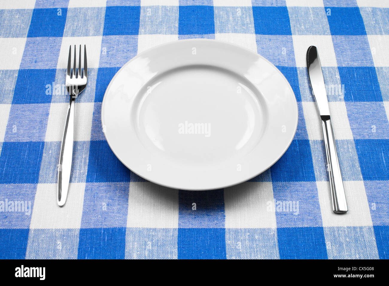 Coltello, piastra bianca e la forcella sul blu tovaglia controllati Foto Stock