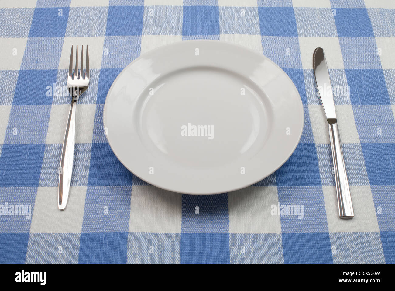 Coltello, piastra bianca e la forcella sul blu tovaglia controllati Foto Stock