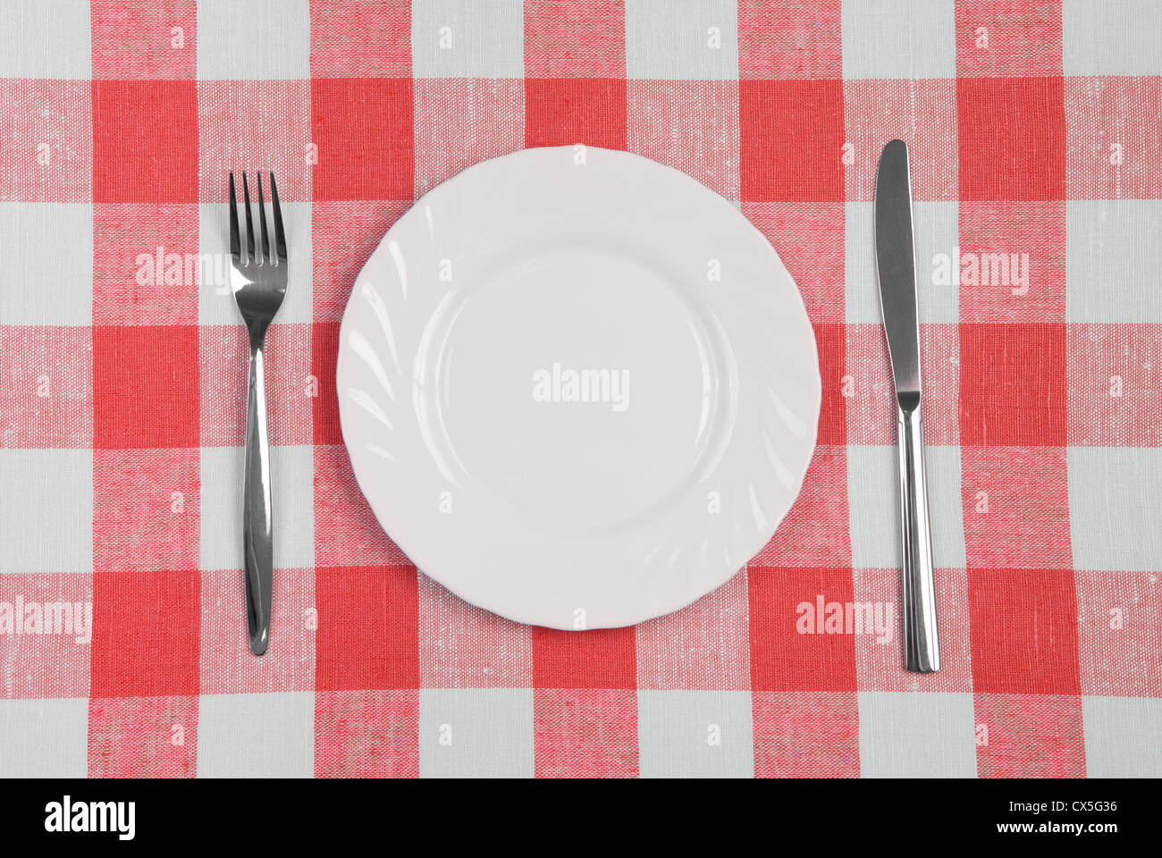 Coltello, piastra bianca e la forcella sul rosso tovaglia controllati Foto Stock
