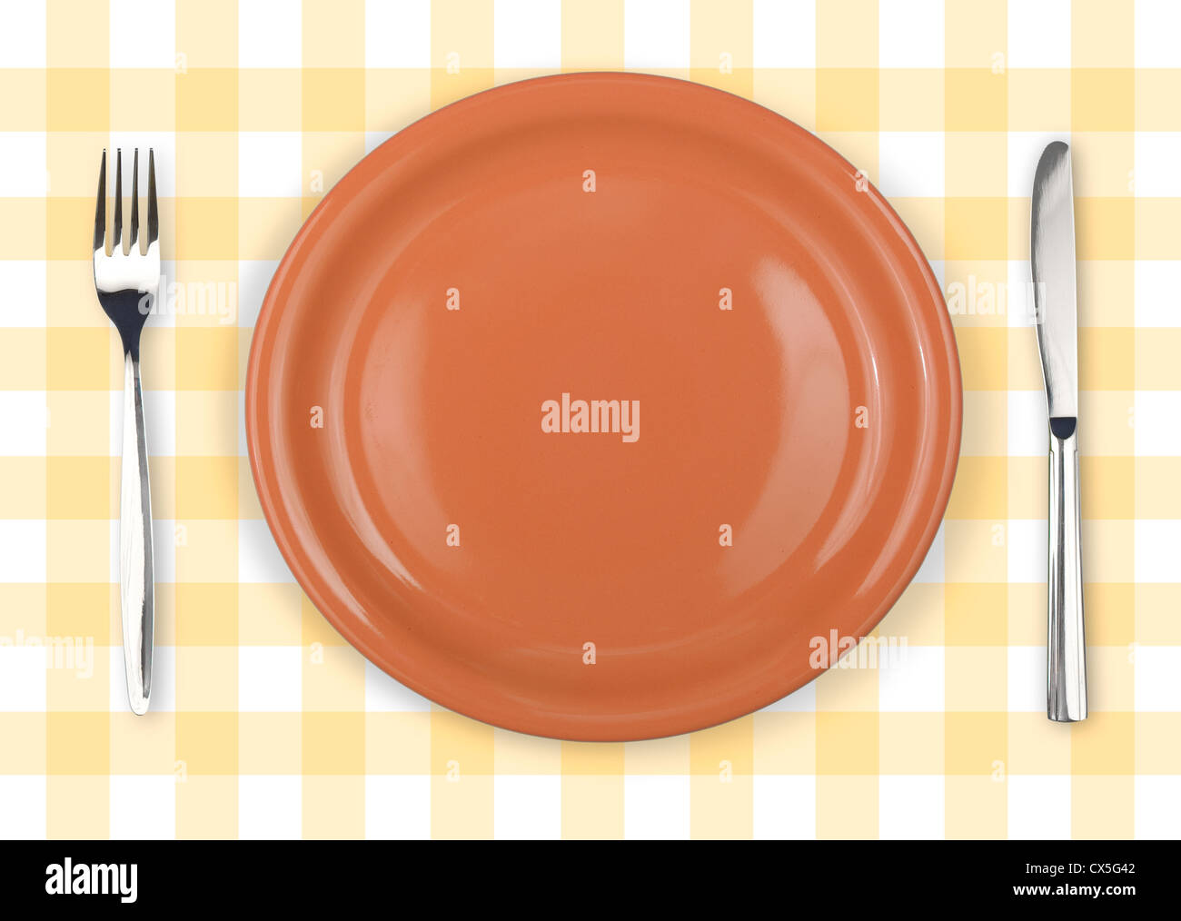 Coltello, arancione e piastra forcella sul giallo tovaglia controllati Foto Stock