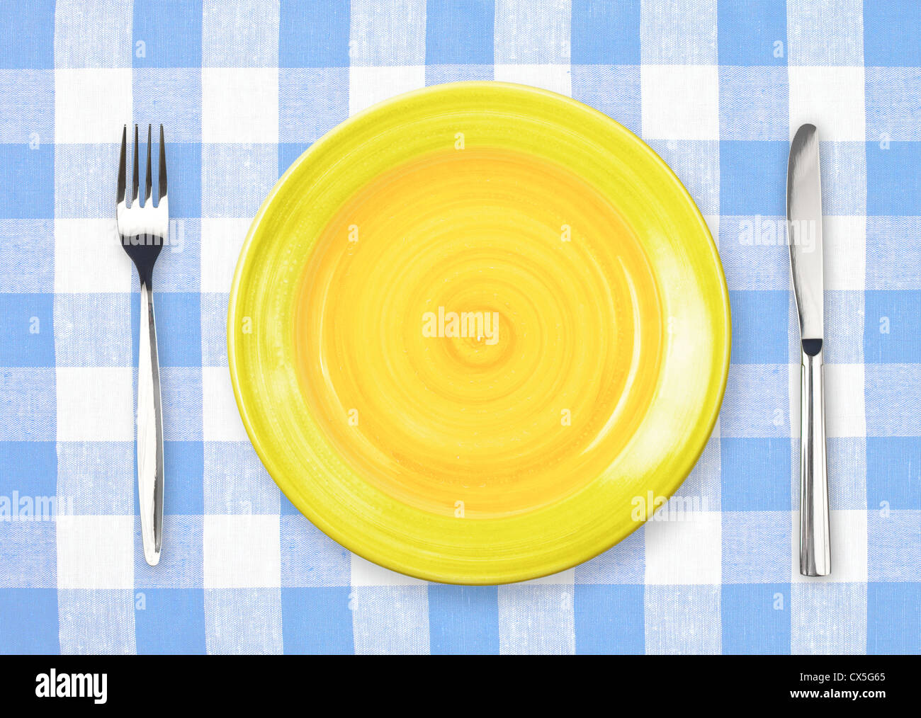 Coltello, piastra di colore giallo e la forcella sul giallo tovaglia controllati Foto Stock