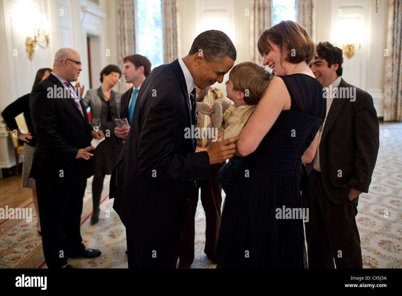 Il presidente statunitense Barack Obama gioca con Leo Chaudhary, figlio della Casa Bianca videografo Arun Chaudhary, destra e Chaudhary la moglie Laura Moser prima di un seder con amici e personale in stato sala da pranzo della Casa Bianca Aprile 18, 2011 in Washington, DC. Foto Stock