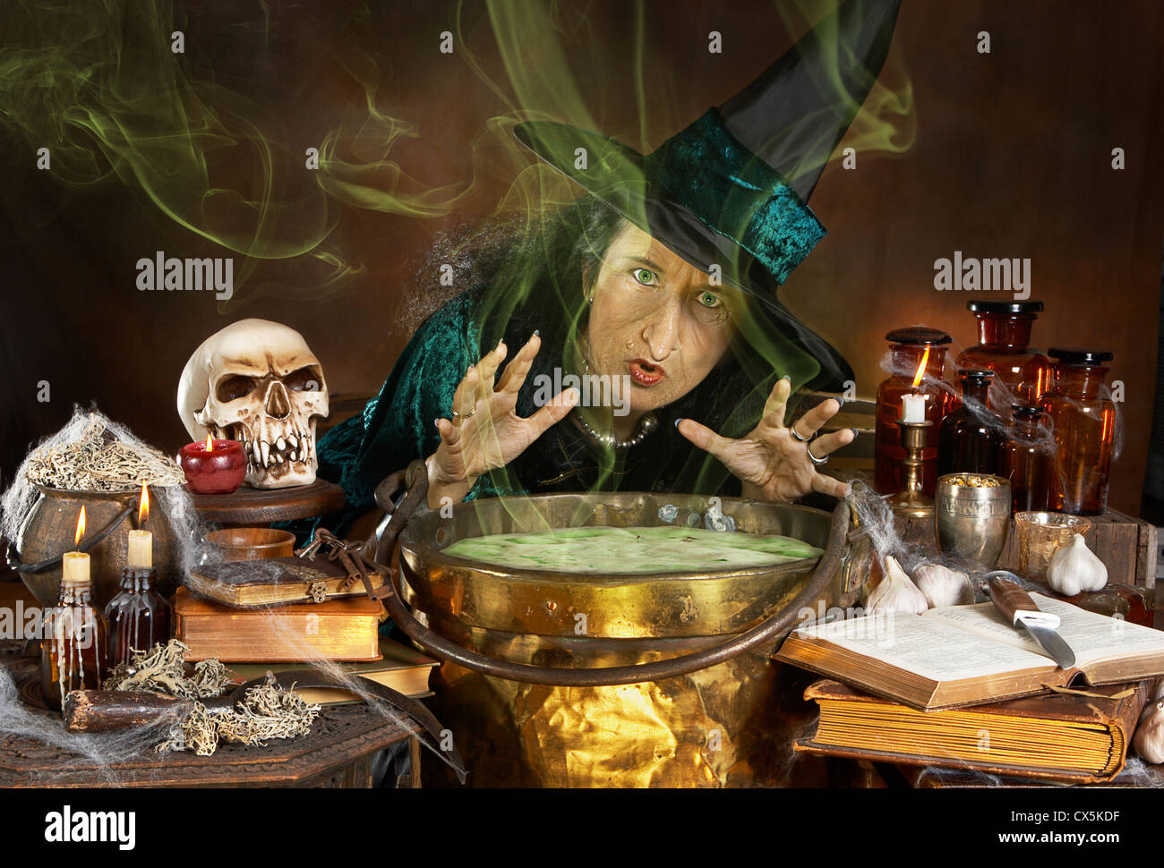Brutta vecchia strega halloween colata di un incantesimo sul suo calderone Foto Stock