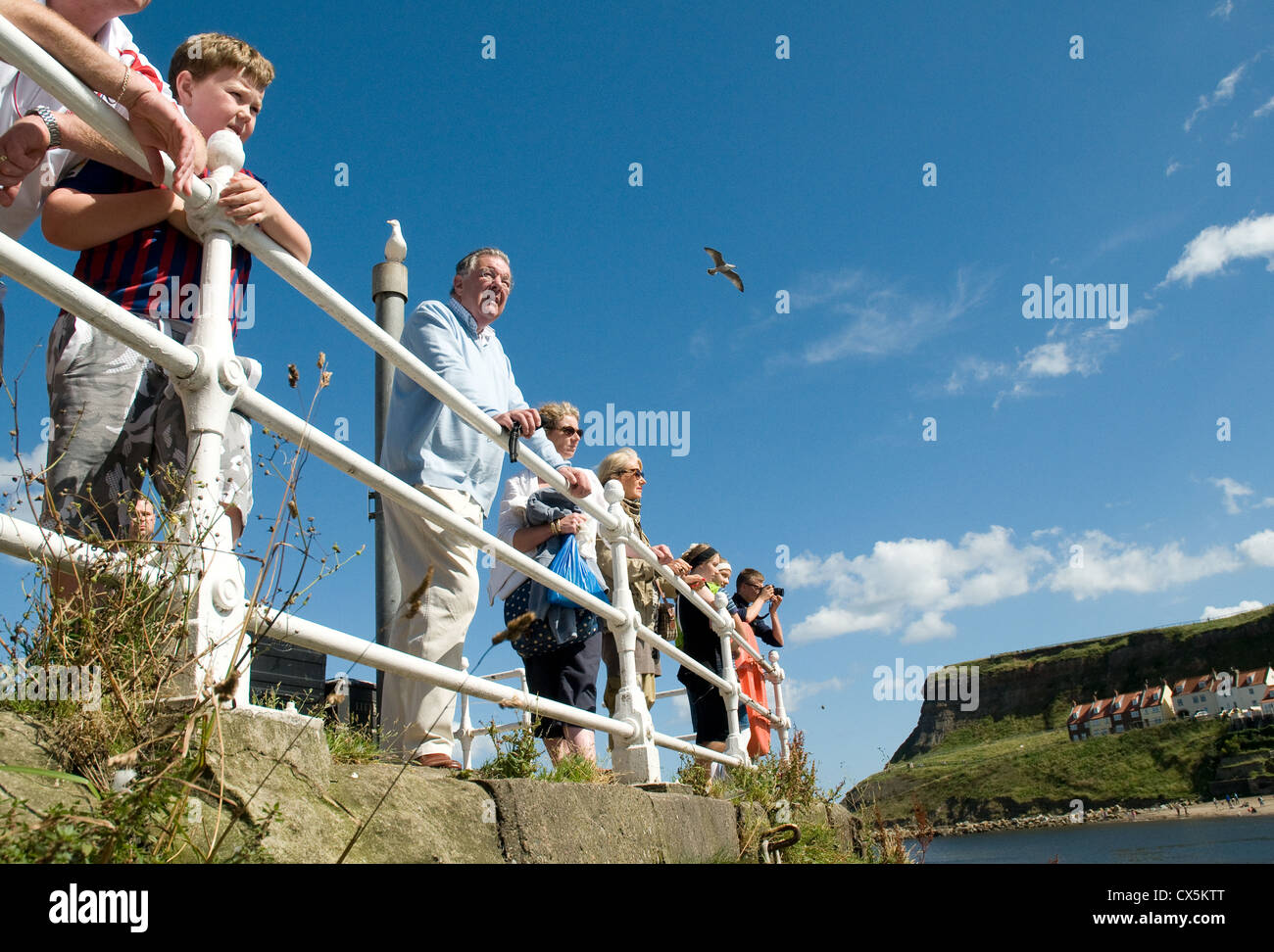 Persone che guardano i siti di Whitby Harbour su un blu luminoso giorno d'estate. Foto Stock