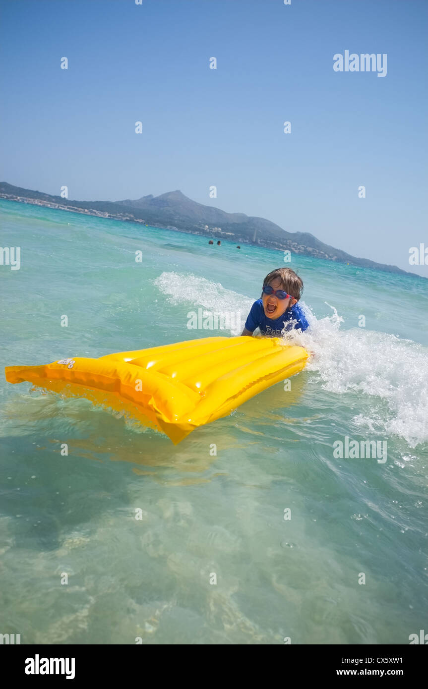 Un giovane ragazzo avente piastre di divertimento nel navigare in mare su di una zattera gonfiabile lilo Foto Stock