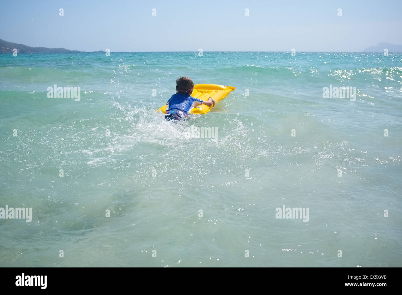 Un giovane ragazzo pagaie in mare su una zattera gonfiabile lilo Foto Stock