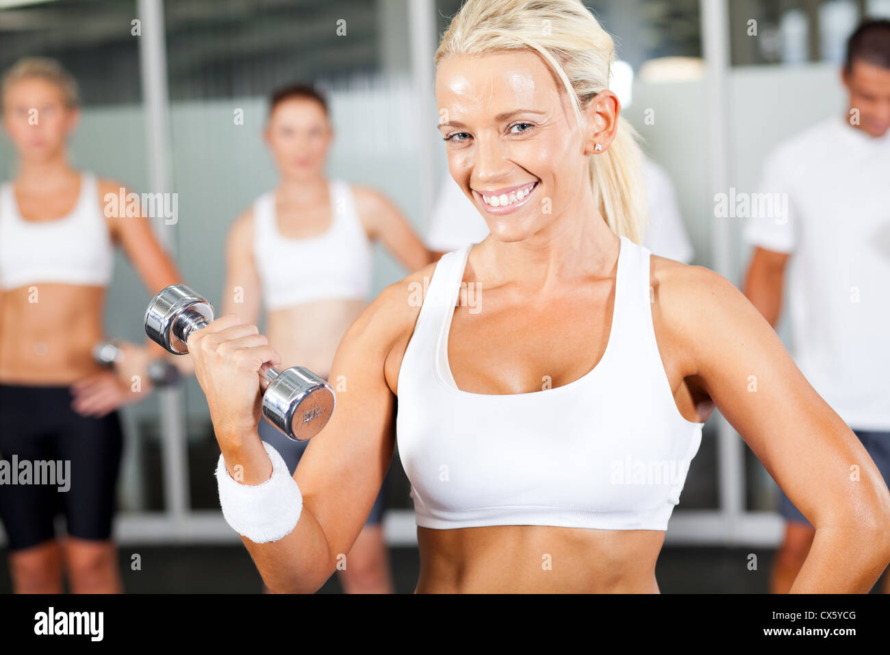 Giovane donna fitness dumbbell facendo esercizio in palestra Foto Stock