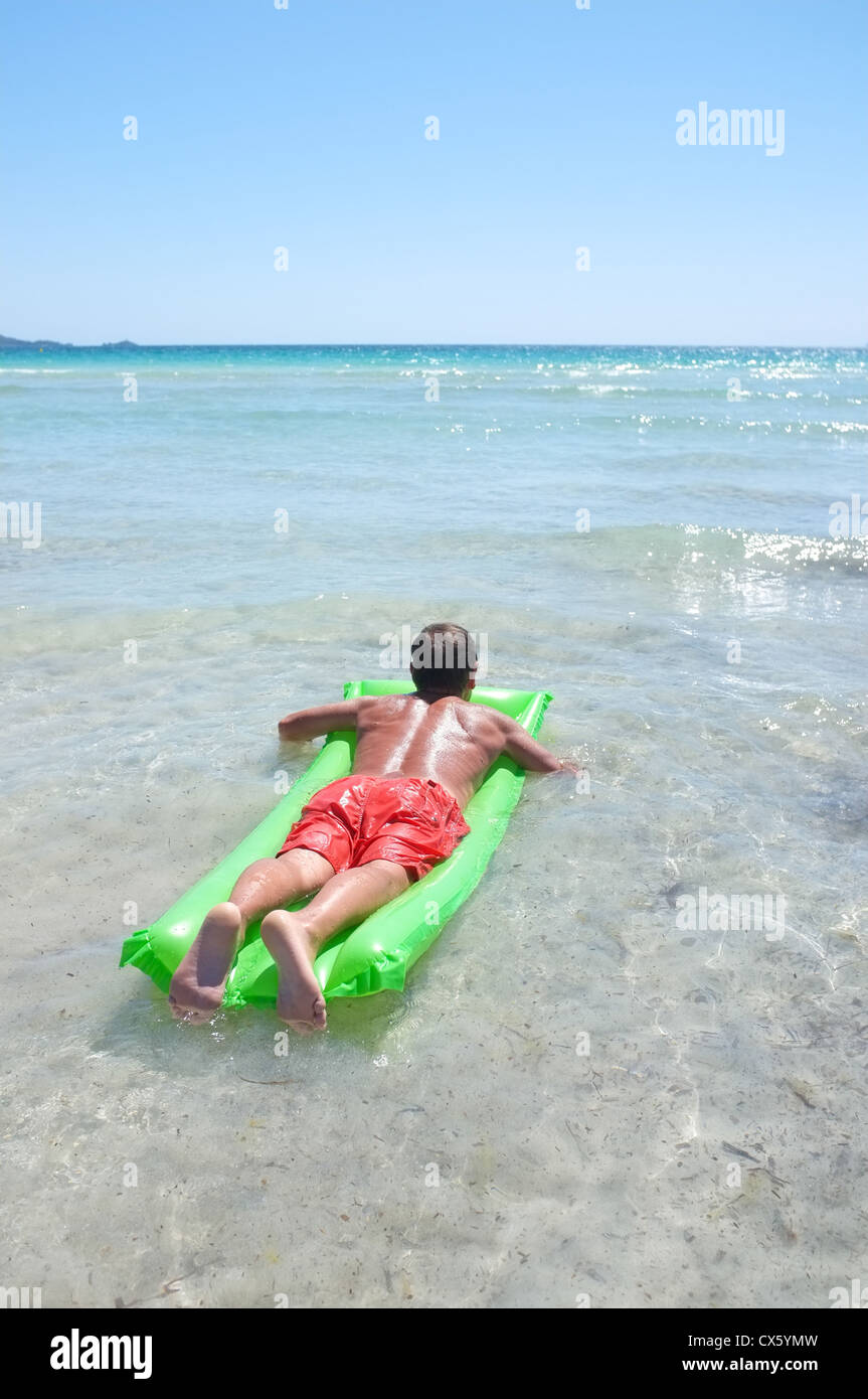 Un uomo giace su un lilo che guarda al mare rilassante in onde mentre sono in vacanza a Maiorca Foto Stock