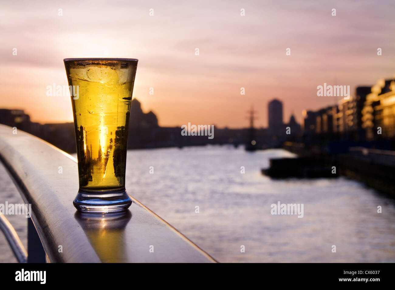 La pinta di birra fredda sul fiume Liffey, al tramonto, oltre lo skyline di Dublino. Foto Stock