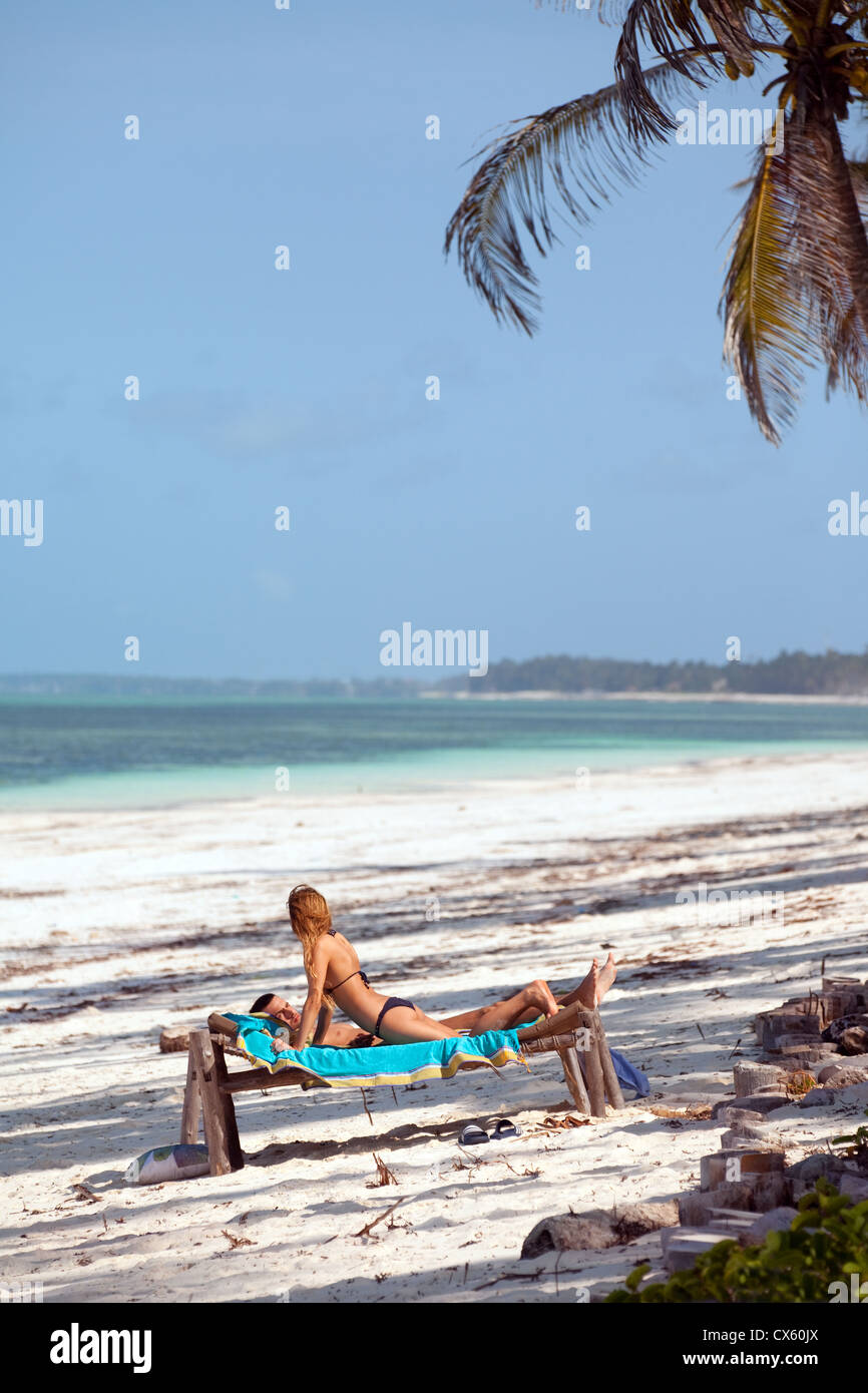Una giovane coppia in vacanza a prendere il sole su una spiaggia deserta, Bjewuu, Zanzibar Africa Foto Stock