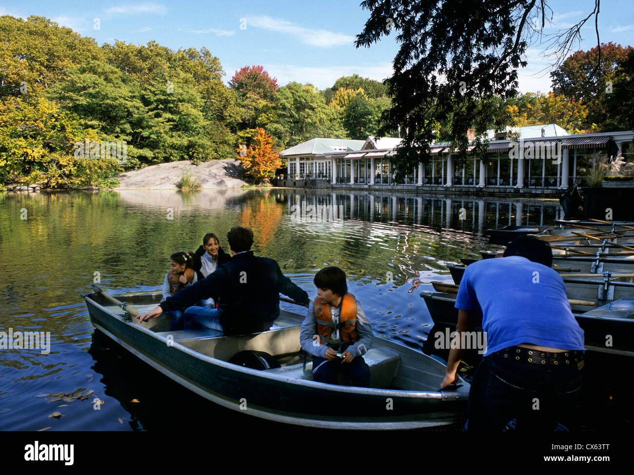 New York City Central Park Lake. Loeb Boathouse in autunno. Attività del Central Park. Gruppo di persone che entrano in barca a remi. STATI UNITI Foto Stock