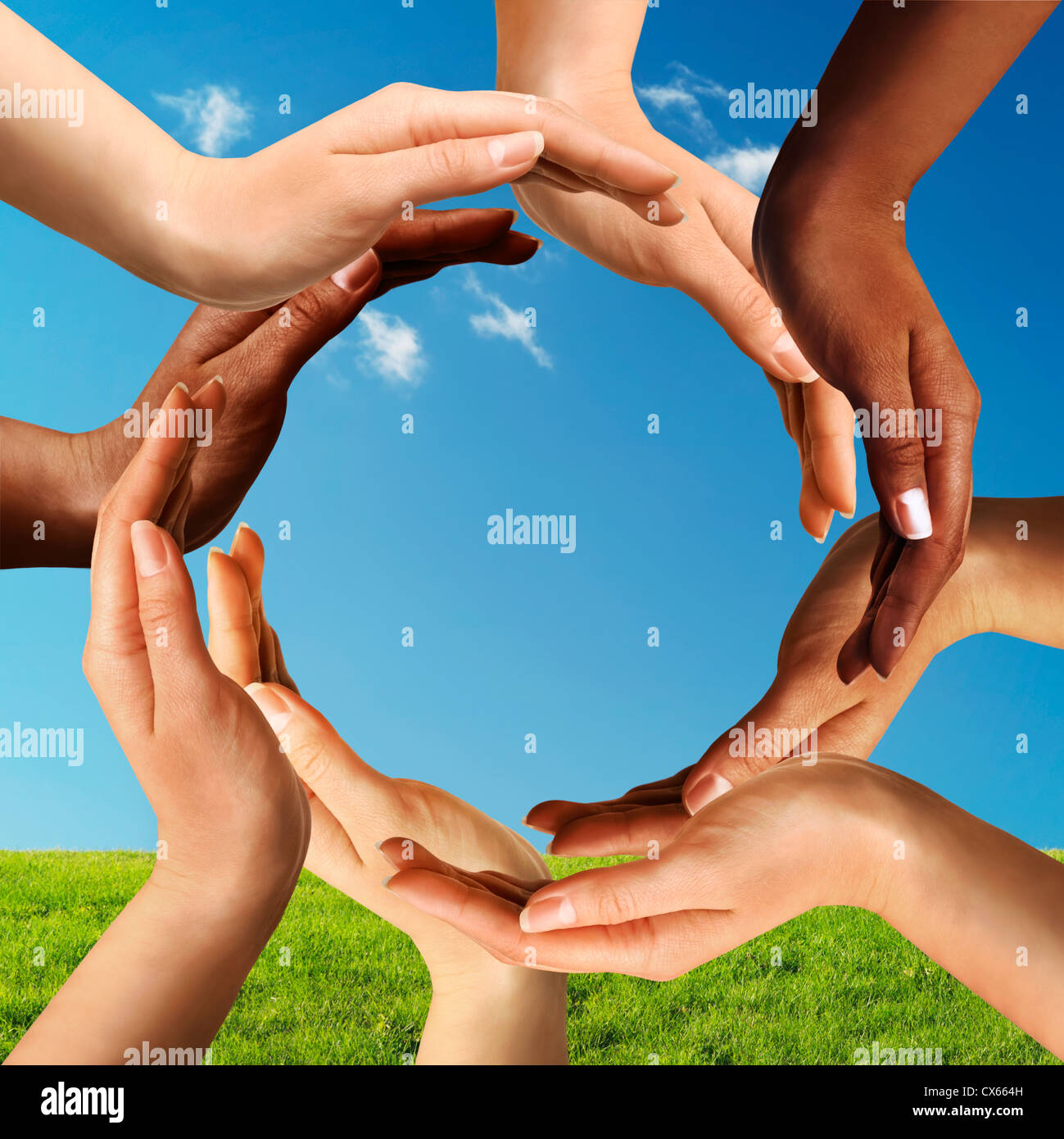 Pace concettuale e la diversità culturale simbolo della multirazziale mani facendo un cerchio insieme sul cielo blu e l'erba verde Foto Stock