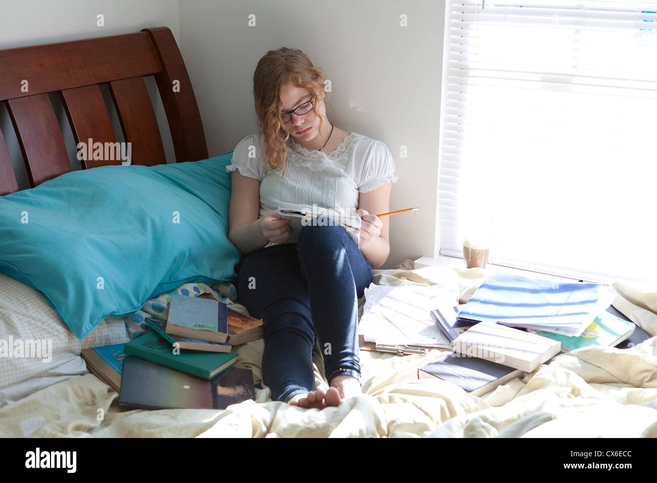 Occupato ragazza con libri di studio sul letto Foto Stock