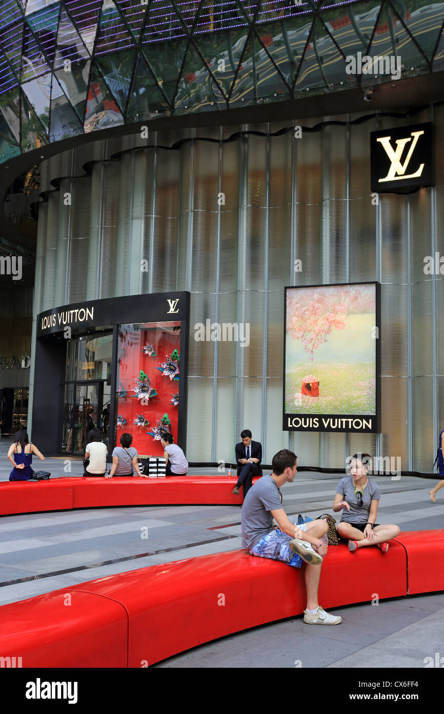 La gente seduta in una area pubblica alla ION Orchard su Orchard Road, Singapore Foto Stock