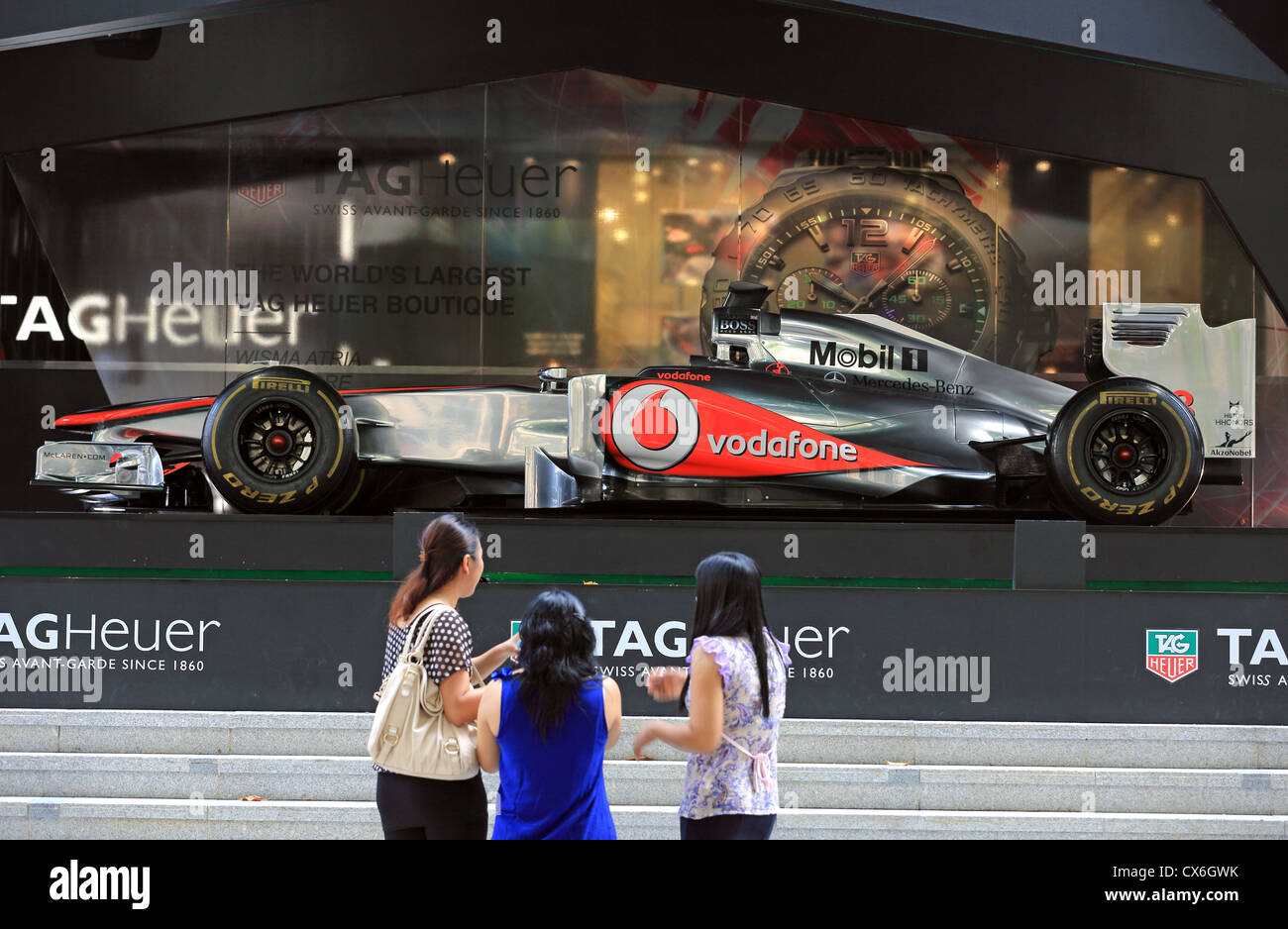 Donna ammirando Jenson Button della McLaren Mercedes Formula One racing car sul display in Singapore prima del Gran Premio di Singapore. Foto Stock