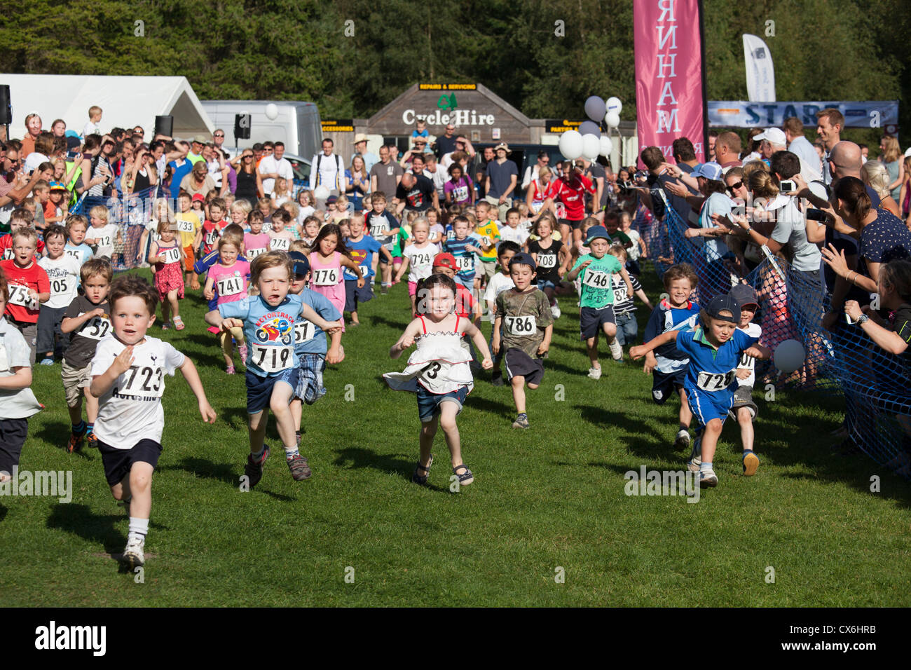 Pre i bambini delle scuole che partecipano a un 60m dash gara con i genitori a guardare a Alice Holt Forest Foto Stock