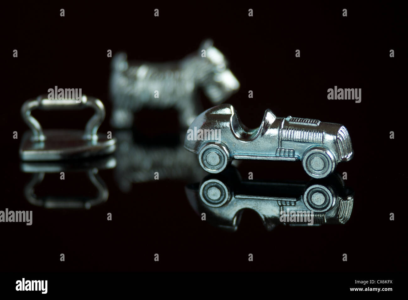 Gioco monopoli pezzi con riflessioni isolate su uno sfondo nero Foto Stock