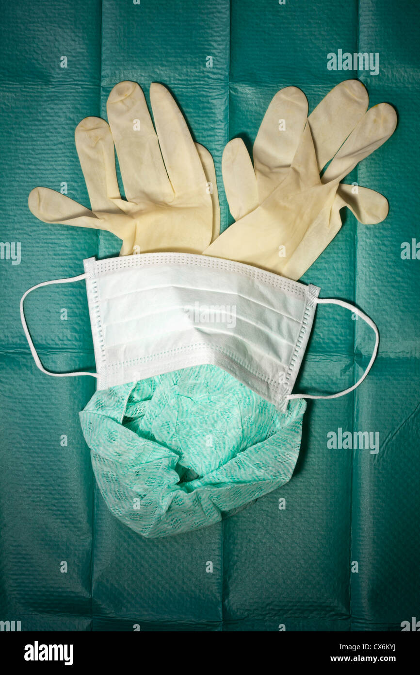 Mascherina chirurgica, cappuccio e guanti di protezione disposti su un telo chirurgico Foto Stock