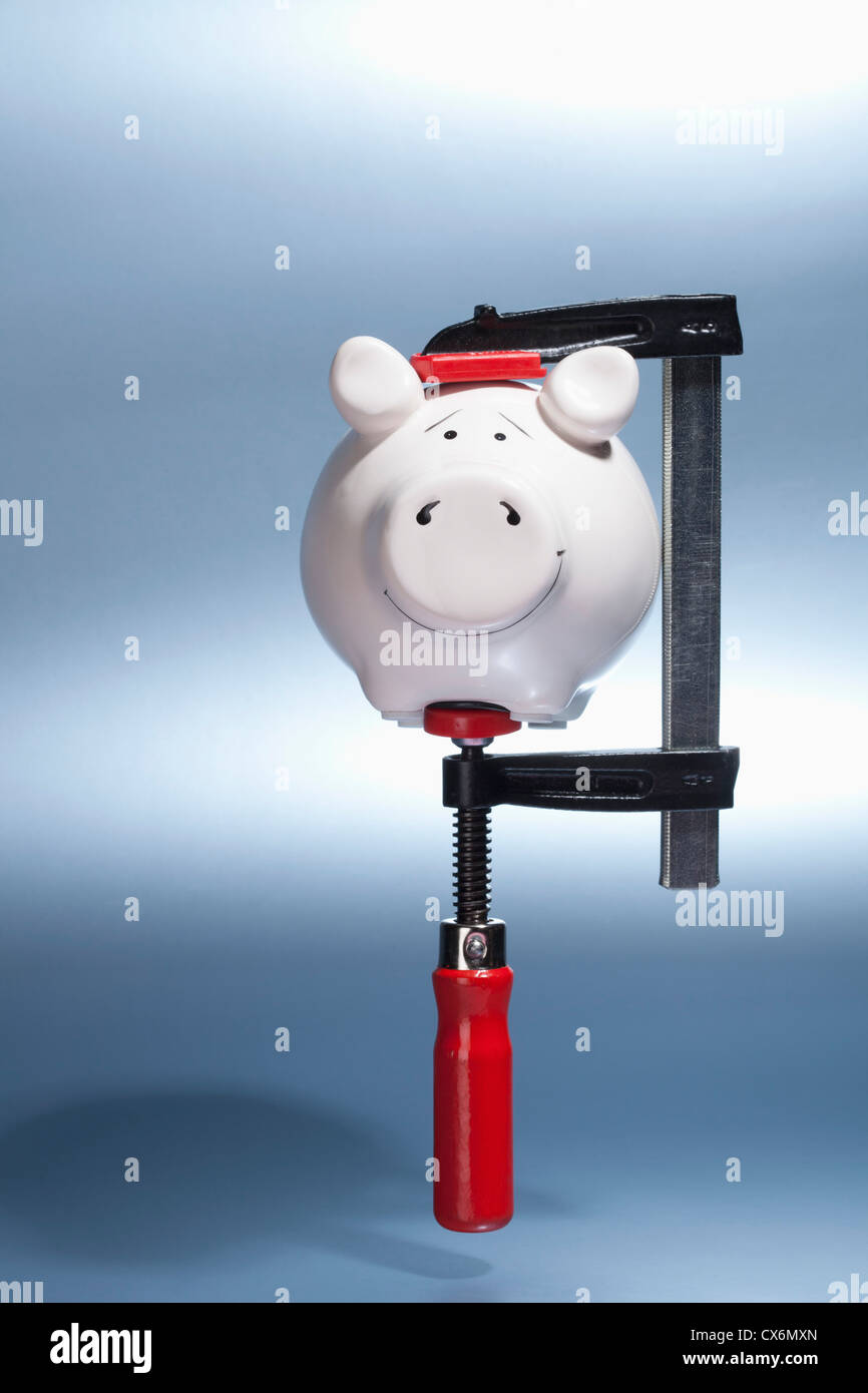 Un salvadanaio essendo trattenuto in una morsa la presa sospesa a mezz aria Foto Stock