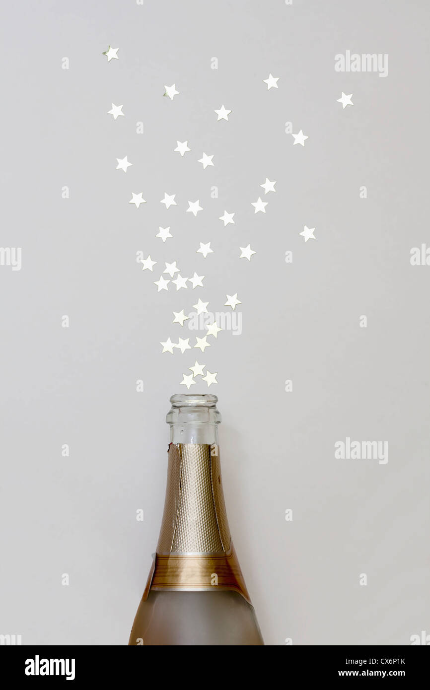 A forma di stella coriandoli fuori di spruzzatura di una bottiglia di champagne Foto Stock