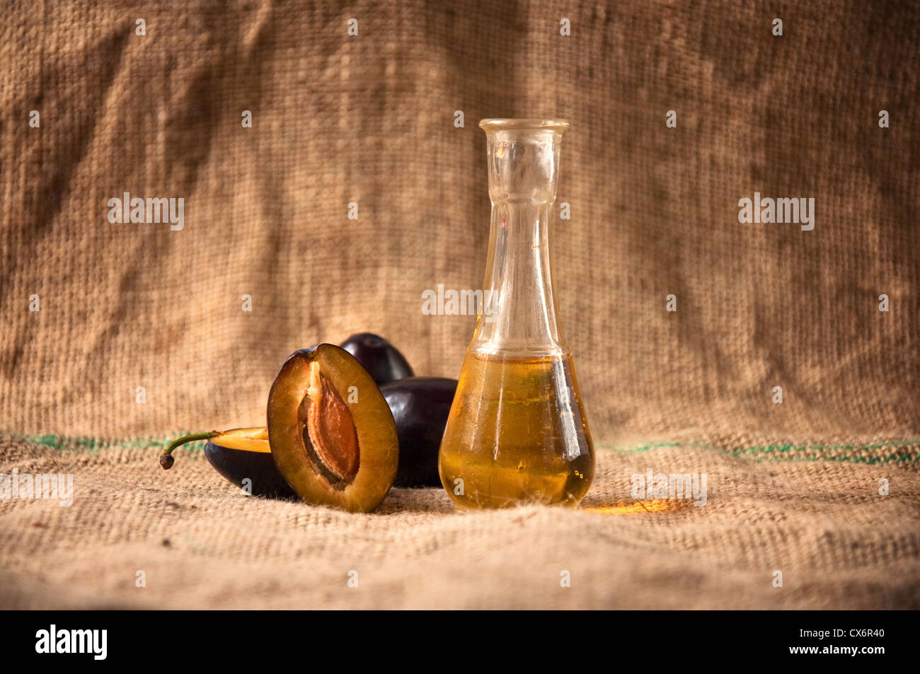 Acquavite di prugne o di grappa con fresco e gustoso frutto di prugne su una tovaglia Foto Stock