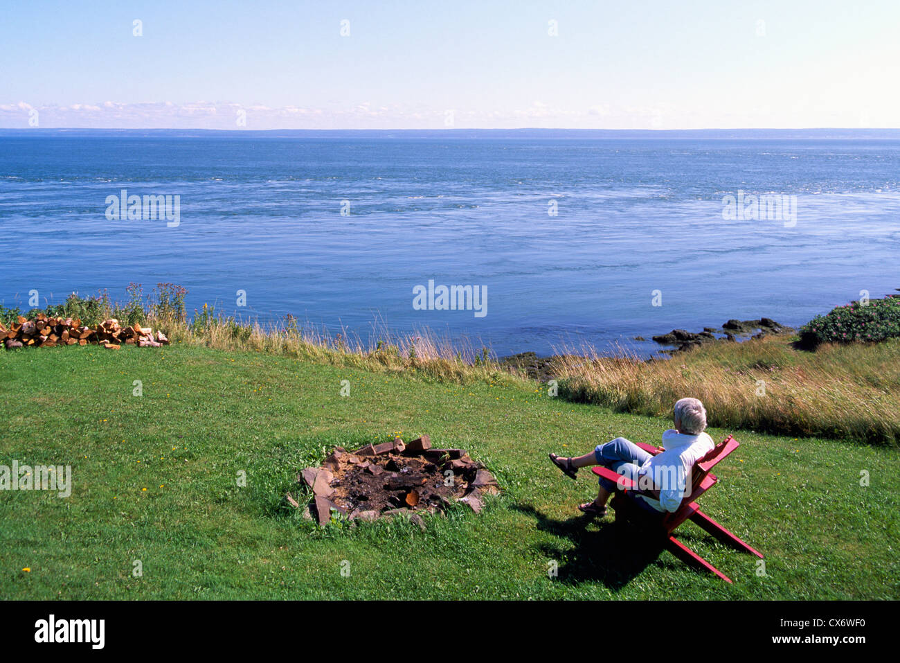 Capo d'Or, Nova Scotia, Canada - donna seduta in cattedra godendo di vista del litorale lungo la baia di Fundy affacciato sul Bacino di Minas Foto Stock