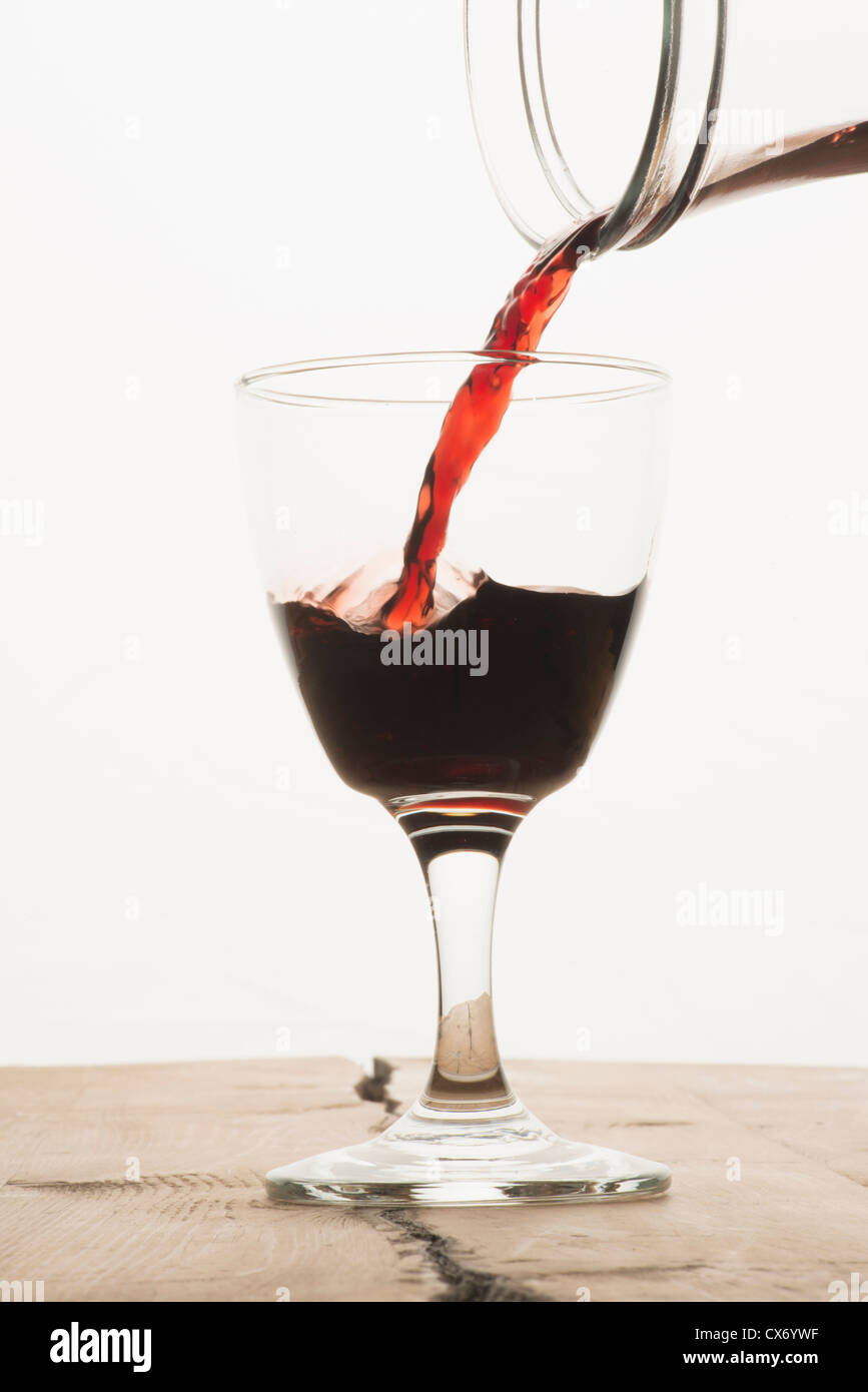 Un bicchiere di vino rosso di essere riempita da una caraffa Foto Stock