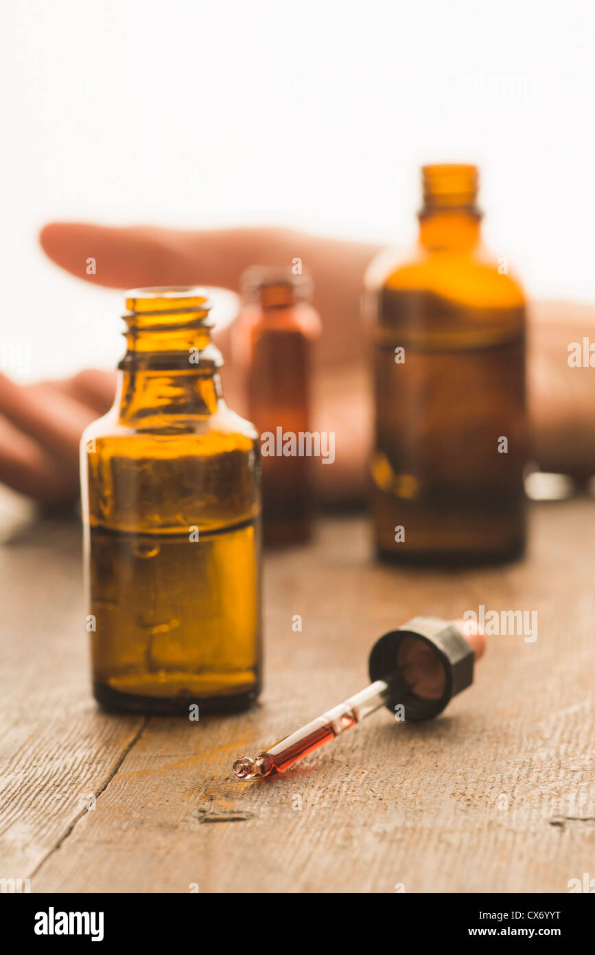 Bottiglie di medici e pipettare contenenti sostanze tossiche fluido con la vittima di un reato in background Foto Stock