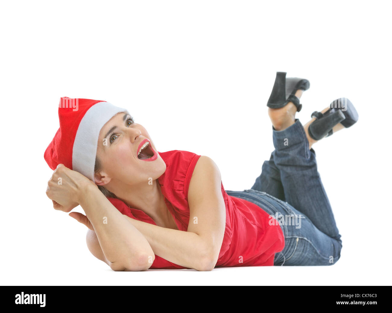 Donna felice nel cappello di Natale la posa sul pavimento e guardando su uno spazio di copia Foto Stock