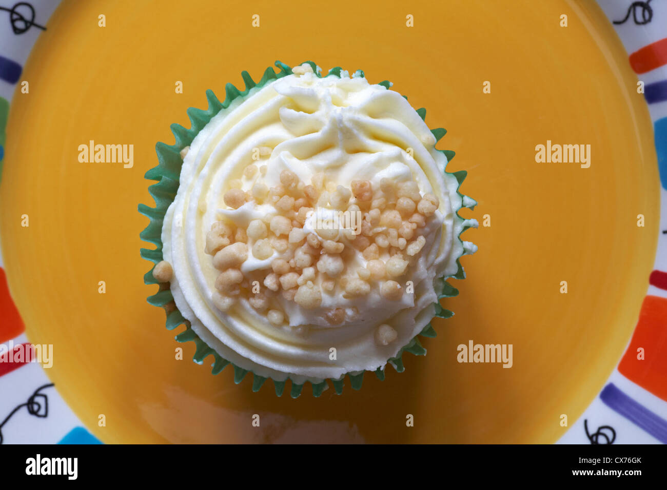 Guardando verso il basso su apple crumble cupcake sulla piastra di colore giallo - decorato a mano tortini di vaniglia riempito con piccante salsa di mele - dal di sopra Foto Stock