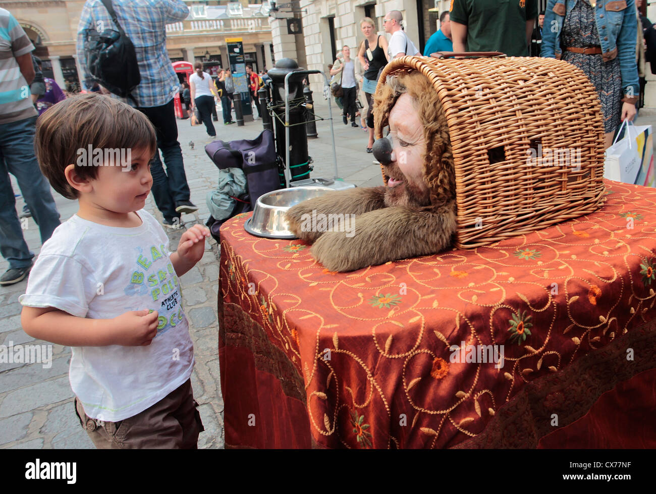 Bambino guardando una strada statua umana vestito come un cane in Covent Garden, Londra centrale Foto Stock