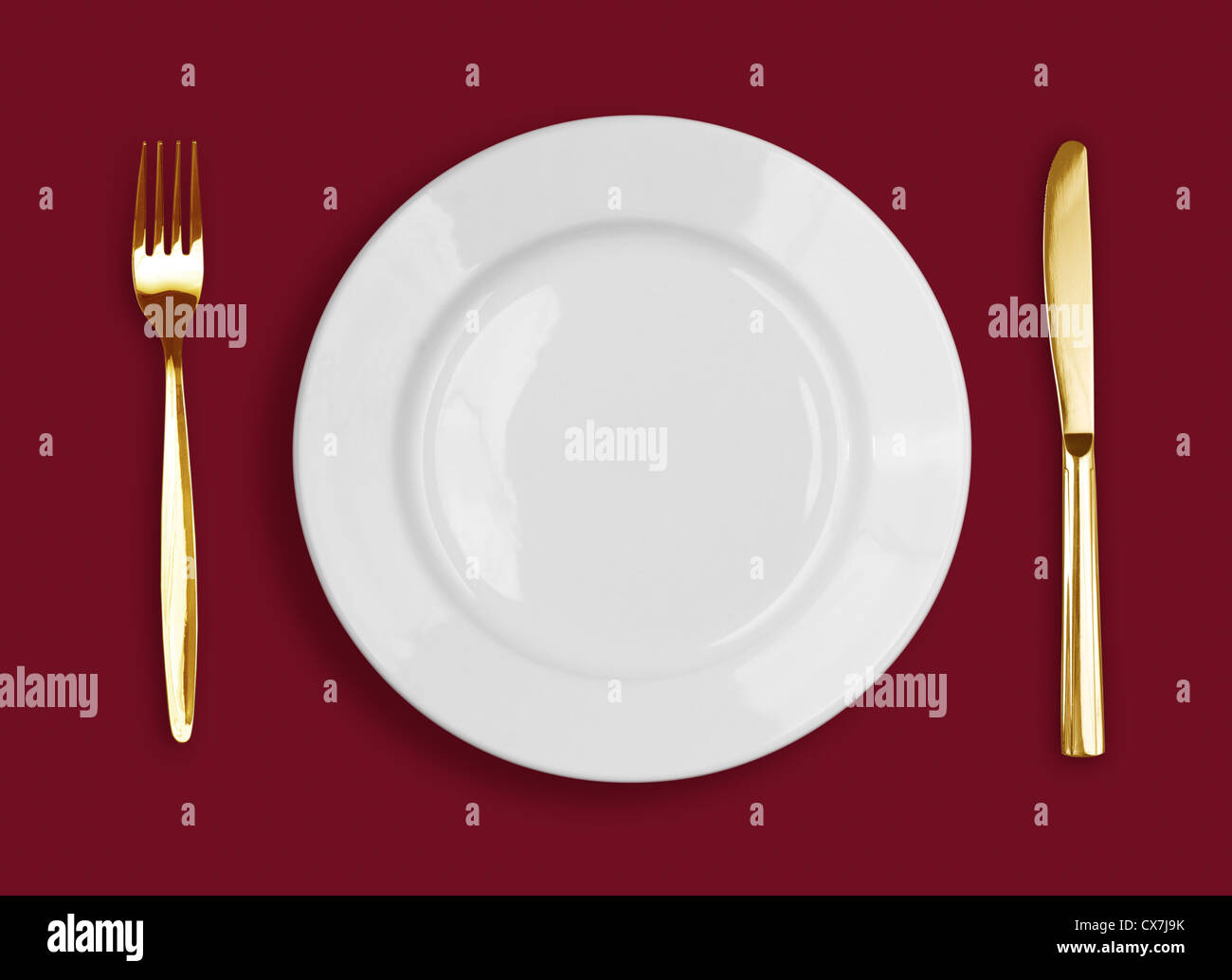 Golden coltello, forchetta e piastra bianca su sfondo rosso Foto Stock